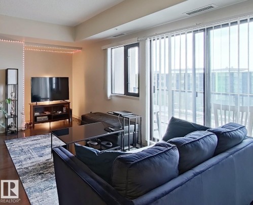 Open-concept living area featuring wood-finish flooring and neutral wall tones - 707 10319 111 Street Nw, Edmonton, AB - Indoor Photo Showing Living Room