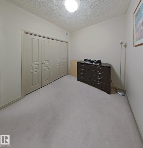 Carpeted room featuring a ceiling-mounted light fixture and light-toned walls - 707 10319 111 Street Nw, Edmonton, AB - Indoor
