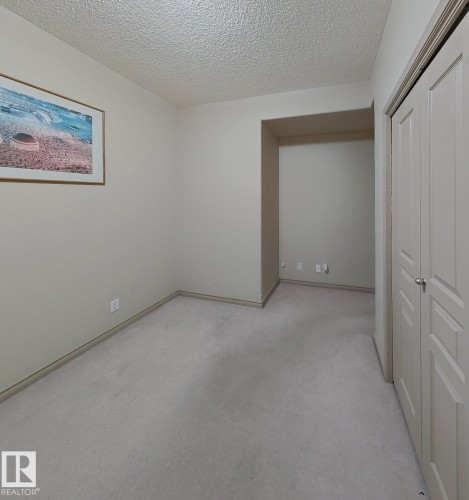 Carpeted room with neutral wall tones and a built-in alcove - 707 10319 111 Street Nw, Edmonton, AB - Indoor Photo Showing Other Room