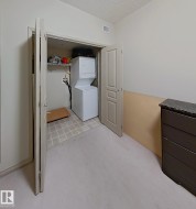 Dedicated laundry closet with stacked washer and dryer, tile flooring, and integrated shelving - 
