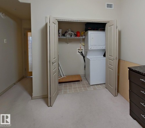 Utility closet featuring stacked laundry appliances and tile flooring - 707 10319 111 Street Nw, Edmonton, AB - Indoor Photo Showing Laundry Room