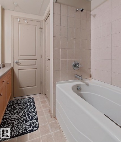 Integrated bathtub and shower with beige tiled surround - 707 10319 111 Street Nw, Edmonton, AB - Indoor Photo Showing Bathroom