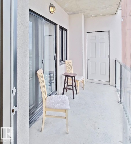 Private balcony featuring concrete flooring, a white six-panel door, and glass panel railing - 707 10319 111 Street Nw, Edmonton, AB -  Photo Showing Other Room