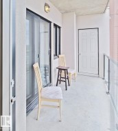 Private balcony featuring concrete flooring, a white six-panel door, and glass panel railing - 