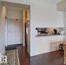 Open-concept kitchen featuring stainless steel appliances, dark wood-finish flooring, and a recessed counter - 707 10319 111 Street Nw, Edmonton, AB  - Indoor 