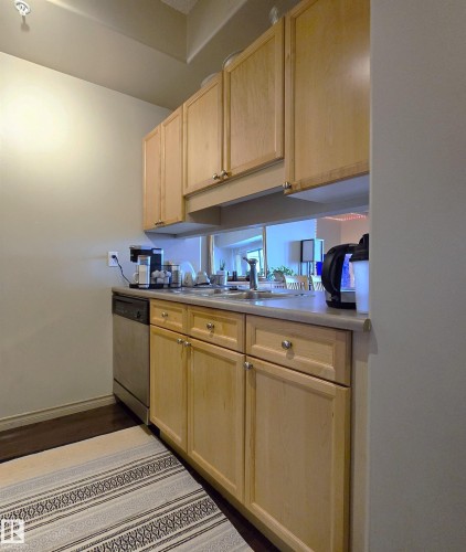 Kitchen featuring light wood cabinetry, a stainless steel dishwasher, a single basin sink with a chrome faucet, and light-toned countertops - 707 10319 111 Street Nw, Edmonton, AB - Indoor Photo Showing Kitchen