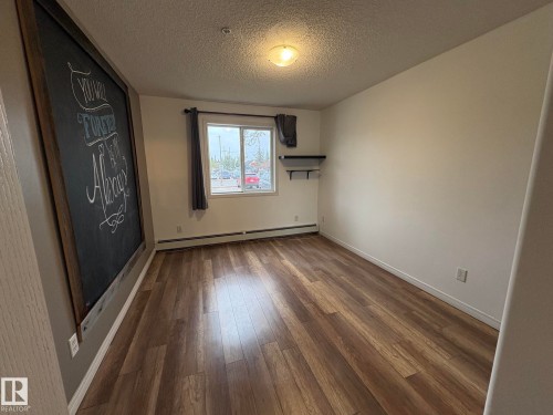 Room featuring wood-finish flooring, white baseboards, a single window, and a built-in wall shelf - 138 9525 162 Avenue, Edmonton, AB 