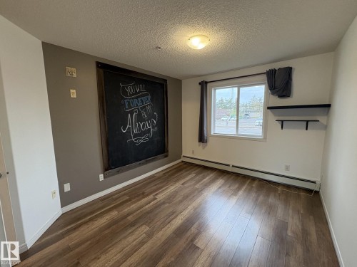 Open concept room with wood-finish flooring and a built-in chalkboard wall feature - 138 9525 162 Avenue, Edmonton, AB 