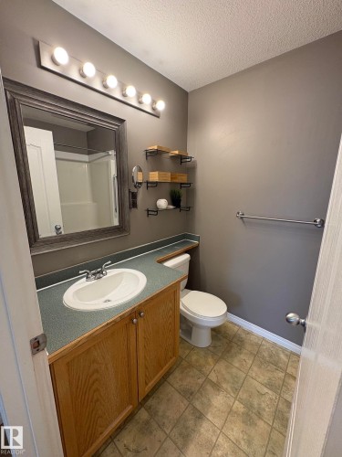 Bathroom featuring a light wood-finish vanity with a built-in sink, gray countertop, and overhead vanity lighting - 138 9525 162 Avenue, Edmonton, AB 