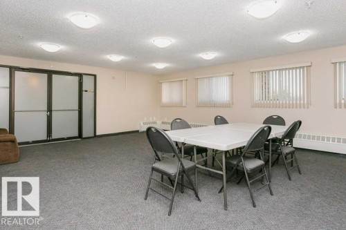 Spacious room featuring neutral carpeting, multiple windows with vertical blinds, and flush-mount ceiling lighting - 138 9525 162 Avenue, Edmonton, AB 