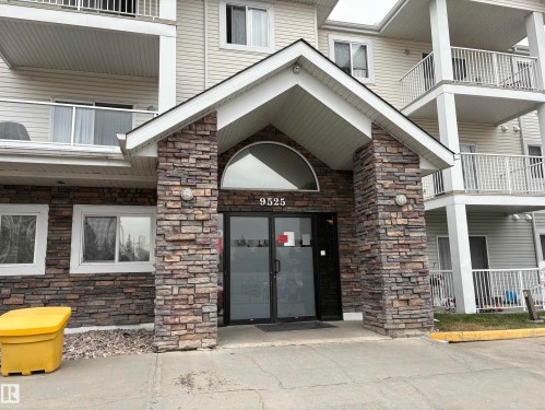 Building entrance featuring a stone facade, prominent covered entryway, and arched transom window - 138 9525 162 Avenue, Edmonton, AB 
