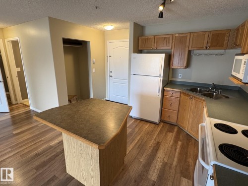 Kitchen with wood-finish flooring and a built-in island - 138 9525 162 Avenue, Edmonton, AB 