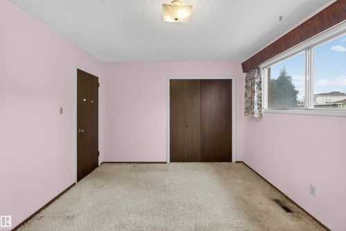 Room featuring carpeted flooring, a window with a wood-finish pelmet, two dark wood-finish doors, and an overhead lighting fixture - 8407 150 Avenue, Edmonton, AB - Indoor Photo Showing Other Room