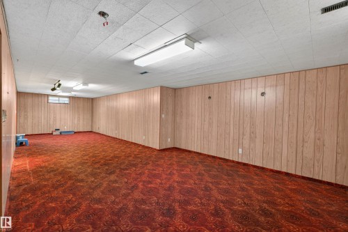 Spacious room with wood-paneling walls and a dropped ceiling with fluorescent lighting - 8407 150 Avenue, Edmonton, AB - Indoor Photo Showing Other Room