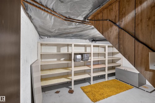 Basement area featuring a concrete floor, built-in shelving, and wood-paneled walls - 8407 150 Avenue, Edmonton, AB - Indoor Photo Showing Other Room
