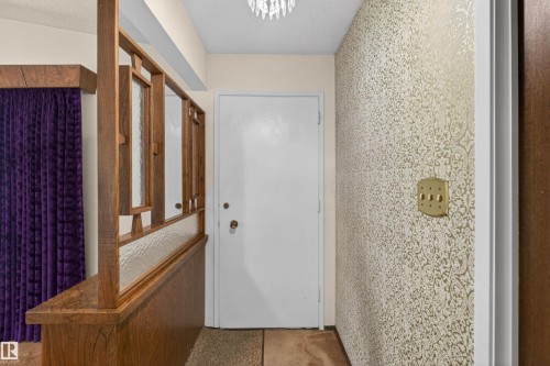 Entryway featuring a white door, textured wallpaper, and an ornate wood-and-glass divider - 8407 150 Avenue, Edmonton, AB - Indoor Photo Showing Other Room
