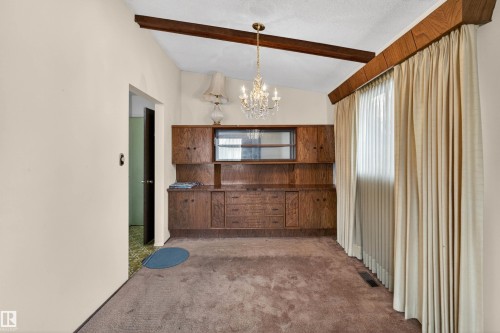 Built-in wood-finish cabinetry featuring upper glass-front display cabinets and lower drawer storage - 8407 150 Avenue, Edmonton, AB - Indoor Photo Showing Other Room