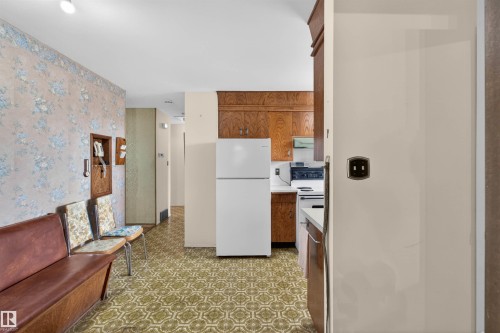 Kitchen area featuring wood cabinetry, white appliances, and patterned floor tile - 8407 150 Avenue, Edmonton, AB - Indoor Photo Showing Kitchen