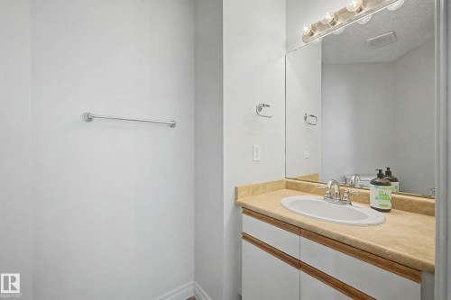 Bathroom vanity featuring a light-toned countertop with an integrated sink and chrome faucet - 16211 55A Street, Edmonton, AB - Indoor Photo Showing Bathroom