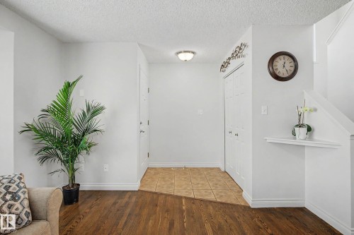 Entryway featuring wood-finish flooring transitioning to ceramic tile, a white bi-fold closet, and a built-in wall shelf - 16211 55A Street, Edmonton, AB - Indoor Photo Showing Other Room