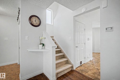 Carpeted staircase with white balustrade, wood-finish flooring, and a built-in wall shelf - 16211 55A Street, Edmonton, AB - Indoor Photo Showing Other Room