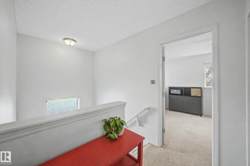 Carpeted hallway with white walls and a white painted banister - 16211 55A Street, Edmonton, AB - Indoor Photo Showing Other Room
