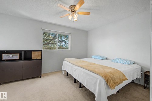 Carpeted room featuring a ceiling fan with light fixture, a window with a roller shade, and light gray painted walls - 16211 55A Street, Edmonton, AB - Indoor Photo Showing Bedroom
