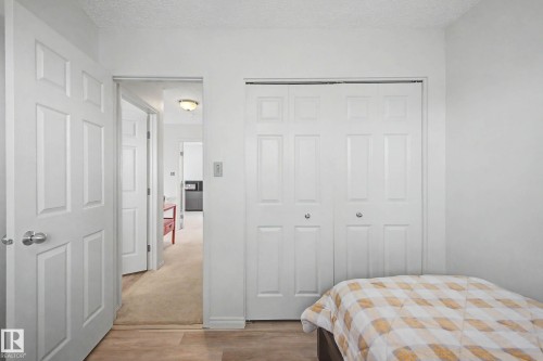 White paneled doors, light wood-finish flooring, and a bi-fold closet - 16211 55A Street, Edmonton, AB - Indoor Photo Showing Bedroom