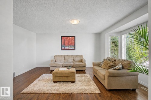 Living space featuring wood-finish flooring, white walls, and a large bay window - 16211 55A Street, Edmonton, AB - Indoor Photo Showing Living Room