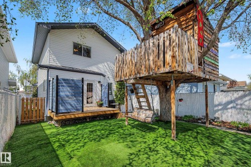 Backyard featuring a built-in treehouse, artificial turf, wood deck with privacy screens, and a swing - 16211 55A Street, Edmonton, AB - Outdoor