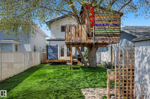 Expansive backyard featuring a treehouse with a wood facade, a manicured artificial turf lawn, and a wooden deck - 16211 55A Street, Edmonton, AB - Outdoor