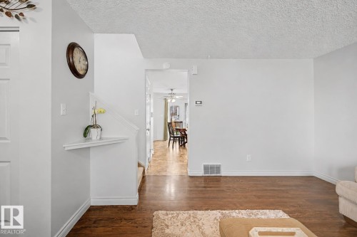 Warm wood-finish flooring complements light wall tones throughout this interior space - 16211 55A Street, Edmonton, AB - Indoor Photo Showing Other Room