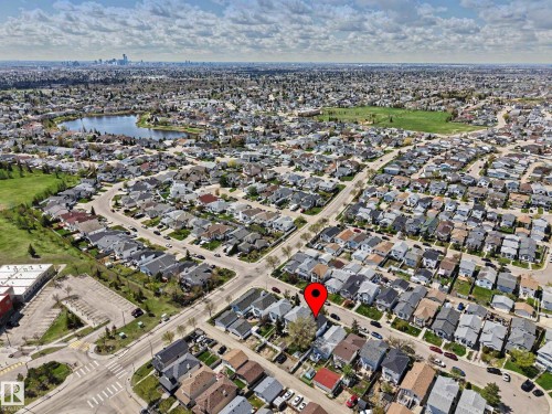 Residential neighborhood featuring a lake, green spaces, and distant city skyline - 16211 55A Street, Edmonton, AB - Outdoor With View