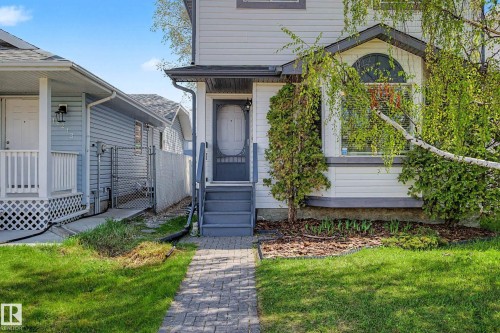 Exterior featuring light-colored siding, a grey entry door with an oval window, and a bay window with an arched transom - 16211 55A Street, Edmonton, AB - Outdoor