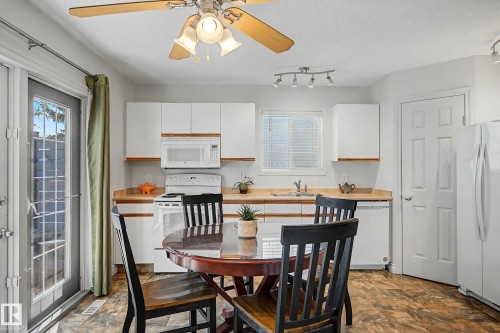 Eat-in kitchen featuring white cabinetry, light wood-finish countertops, and a white appliance suite including a microwave, range, and dishwasher - 16211 55A Street, Edmonton, AB - Indoor Photo Showing Other Room