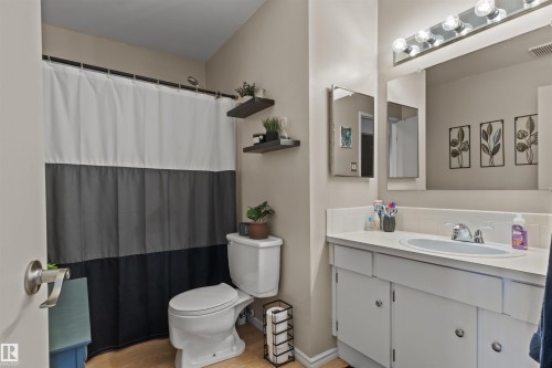 Bathroom featuring a single vanity with built-in cabinetry, an integrated sink, and a large wall-mounted mirror - 6 3803 76 Street, Edmonton, AB - Indoor Photo Showing Bathroom