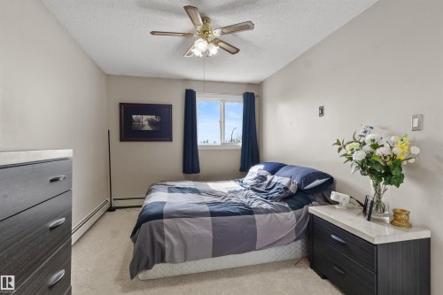 Bedroom featuring light neutral wall paint, a window with dark curtains, and a ceiling fan with integrated lighting - 6 3803 76 Street, Edmonton, AB - Indoor Photo Showing Bedroom