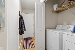 Dedicated laundry area featuring a white washing machine and dryer, overhead wire shelving, and wood-finish flooring - 