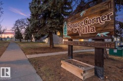 "Spruce Corner Villa" community sign featuring a rustic wood design and a built-in planter box - 