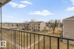 Exterior balcony with black metal railing overlooking a residential complex - 