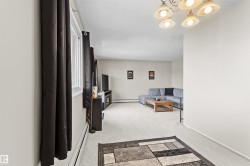 Carpeted living area featuring a large window, warm neutral wall tones, and a multi-light ceiling fixture - 