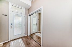 Entryway featuring a white door with frosted glass panel and transom window, wood-finish flooring, and a mirrored closet - 