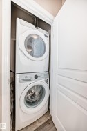 Dedicated laundry closet featuring a stacked washer and dryer unit, white paneled door, and durable tile flooring - 