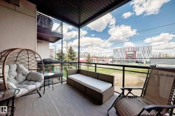Balcony featuring wood-finish flooring, a black metal and glass railing, and a dark soffit - 