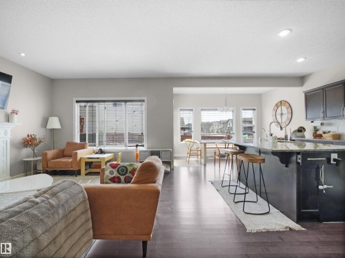 Open-concept living space featuring rich wood-finish flooring throughout - 3247 15 Avenue Nw, Edmonton, AB 
