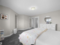 Spacious bedroom featuring neutral wall tones, dark grey carpeting, and white baseboards - 