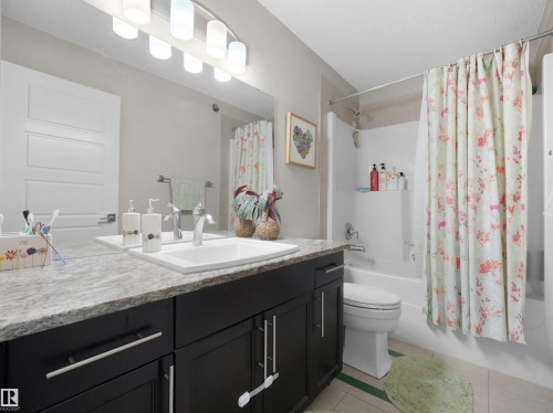 Bathroom featuring a single vanity with dark cabinetry, a light-toned countertop, and an undermount sink - 3247 15 Avenue Nw, Edmonton, AB 