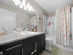 Bathroom featuring a single vanity with dark cabinetry, a light-toned countertop, and an undermount sink - 