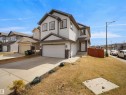 Two-story residence featuring light-colored siding with dark trim accents, a front-facing garage, a concrete driveway, and a front walkway - 3247 15 Avenue Nw, Edmonton, AB 