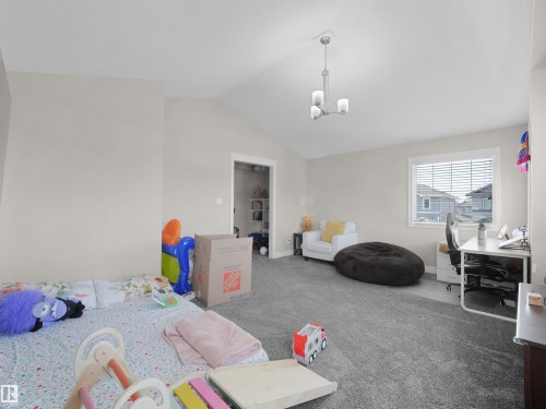 Carpeted room with a vaulted ceiling, a chandelier light fixture, and a window with horizontal blinds - 3247 15 Avenue Nw, Edmonton, AB 